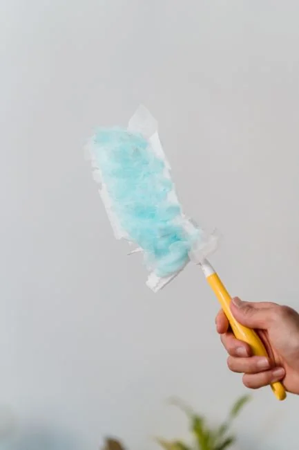 A person in personal protective equipment vacuuming indoors, ensuring a thorough clean.